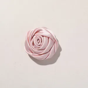 Primer plano detallado de un accesorio rosa de satén, elegante adorno floral de tela fina.