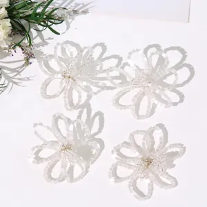 Detailed close-up of handmade white beaded flower components with hollow petals and delicate pistil.