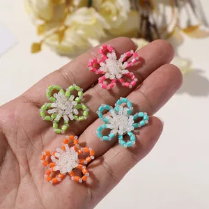 Close-up of colorful DIY beaded flower charms, showcasing delicate tube bead details and texture.
