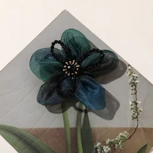 Detailed close-up of dark green organza five-petal flower with crystal bead center for DIY.