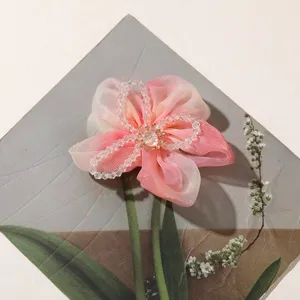 Close-up of pink gradient organdy flower hair tie with crystal bead core detail.