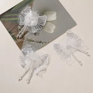 Close-up white sequin chiffon butterfly bow patch with crystal bead tassels for DIY crafts.