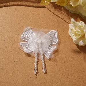 Detailed close-up of white chiffon butterfly patch with sequins, beads, and crystal tassels.