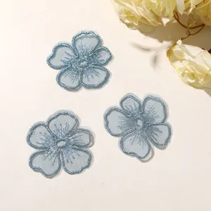 Primer plano detalles de flores de cinco pétalos bordadas en encaje organza azul claro
