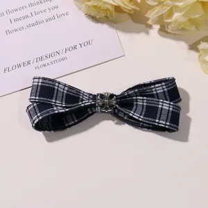 Blue and white plaid bow hair clip with vintage silver cross metal detail, close-up view.