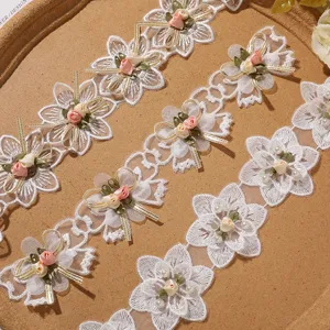 Detail shot of white lace trim with floral embroidery, bows and pearls for DIY sewing projects.