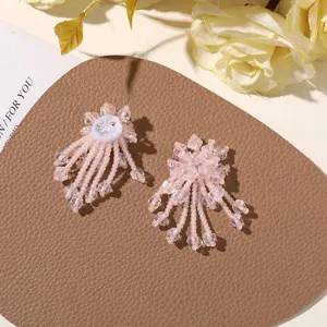 Detalle pendientes de flor con borla de cuentas rosa, estilo caramelo dulce.