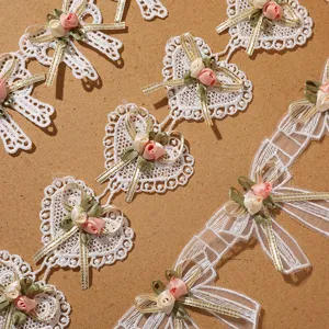 Detailed closeup of white lace trim with cute ribbon bows and fabric flower appliqués.