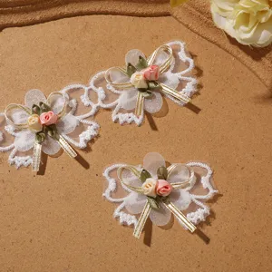 Detailed close-up shot of white lace bow embroidery applique with pink fabric roses.
