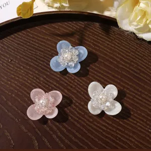 Closeup detail shot of resin four-petal flower charms with crystal beads and pearl core.