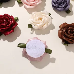 Detailed view of handmade ribbon rose flower accessories with green leaves for DIY crafts.