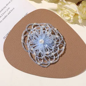 Detail shot of handmade light blue beaded flower accessory with white pearl center, elegant design.