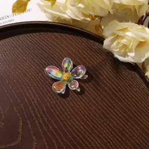 Detail shot of iridescent acrylic flower hair accessory featuring a sparkling rhinestone core.