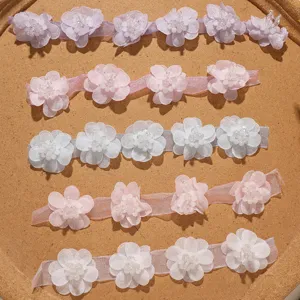 Gros plan de garnitures de fleurs en mousseline avec perles pour accessoires de coiffure DIY.