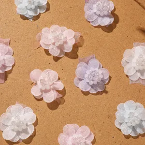 Détails d'applications de fleurs perlées en mousseline texture douce et travail délicat.