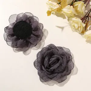 Dettaglio fiore di rosa in garza a pois grigio scuro, accessorio per capelli in tessuto.