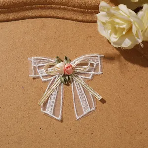 Detailed shot of 3d lace bow flower patch, white mesh ribbon and handmade fabric rose appliques.