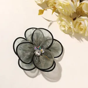 Close-up view of multi-layered mesh flower accessory featuring sparkling rhinestones and black trim.