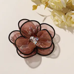 Close-up detail of brown organza mesh flower accessory featuring sparkling crystal center.