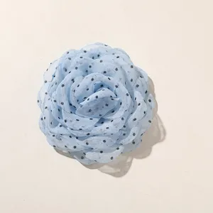 Dettaglio ravvicinato di un fiore di rosa in tulle a pois azzurro per accessori artigianali.
