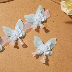 Close-up of light blue mesh beaded butterfly patches with delicate tassel for DIY crafts.