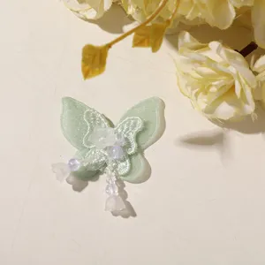 Green tulle butterfly patch detail, beaded tassel accessory for DIY crafts and decor.