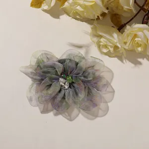 Detailopname van kleurverloop organza bloem broche accessoire met sprankelende strass steen.