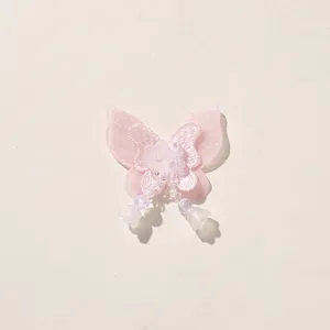 Detailed close-up of pink layered mesh butterfly patch with beads and tassel design accessory.