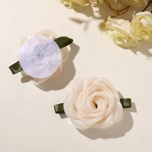 Close-up detail shot of mesh fabric rose hair clips with green ribbon leaves, showing front and back.