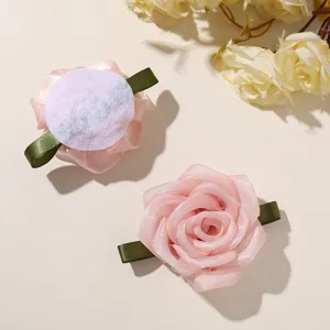 Detail shot of pink mesh ribbon rose flower DIY hair clip accessory with green leaf base.