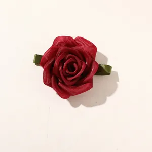 Close-up detail of the red organza mesh rose flower with green leaf ribbon for DIY hair accessories.