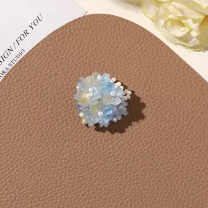 Close-up detail of handmade blue beaded flower accessory, delicate craft and shimmering texture.