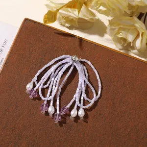 Detailed close-up of handmade beaded crystal tassel accessory featuring purple beads and rhinestones.