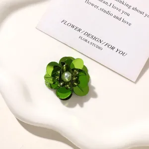 Detailed view of green beaded flower DIY accessory with sparkling sequins and pearl center.