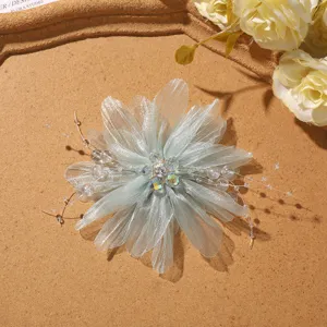 Close-up detail of light green mesh flower accessory with sparkling crystal beaded center and stems.