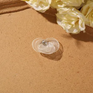Close-up of sheer mesh flower DIY accessory with crystal center on textured background.