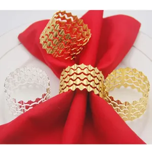 Close-up detail of hollow metal napkin rings in gold and silver finishes on a red cloth napkin.