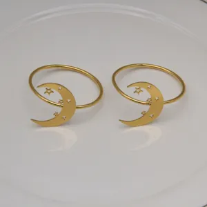 Gold metal napkin rings detail view featuring elegant crescent moon and star cutout design.