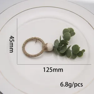 Handmade woven hemp rope napkin ring with wooden bead and green eucalyptus, detail view.