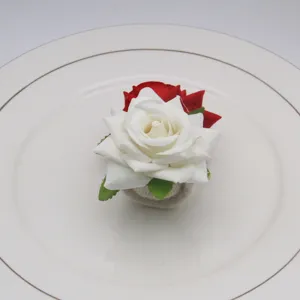 Dettaglio portatovagliolo rosa artificiale, design floreale bianco e rosso per decorare tavola