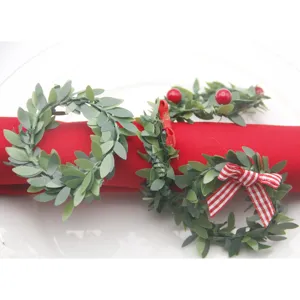 Detailaufnahme von Weihnachts-Serviettenringen mit grünen Blättern und roten Schleifen.