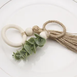 Handmade jute rope napkin ring with wooden beads and green leaf decor for rustic table setting.