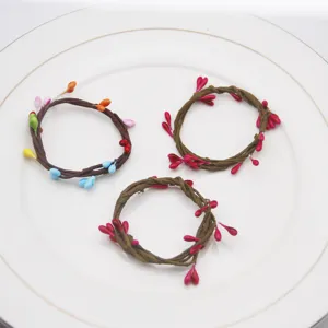 Handmade woven vine napkin rings with colorful berry decor, perfect for party table settings.