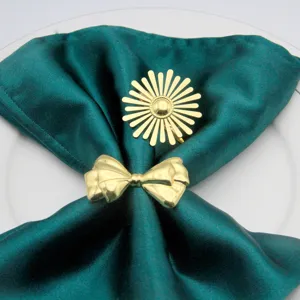 Detail shot of golden sunburst and bow napkin rings on green silk napkin for table decor