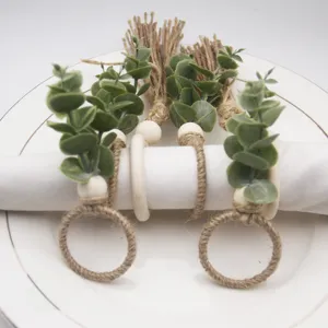 Rustic handmade jute rope napkin ring with wooden beads and eucalyptus leaf decor detail.