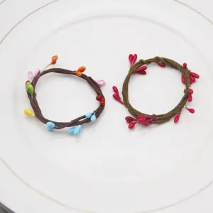 Handmade vine napkin rings with colorful berry accents, perfect for party table decor and daily use.