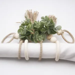 Handmade woven jute rope napkin rings with wooden beads and tassels for pastoral table decor.