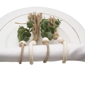 Handmade rustic napkin rings with wooden beads, jute tassels, and artificial leaves for table decor.