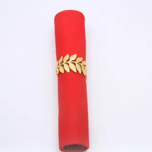 Gold metal leaf napkin ring with red fabric napkin for elegant table setting decor.
