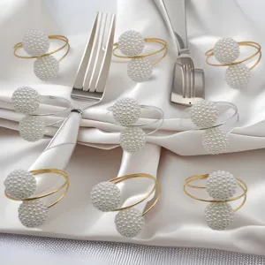 Detailed view of elegant pearl napkin rings with gold and silver metal rings for hotel table decor.